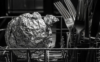 Aluminum foil ball in dishwasher basket next to silverware